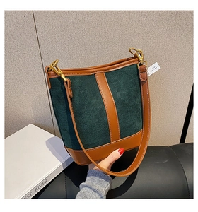 Detail of dark green suede bucket bag with brown leather trim and gold hardware