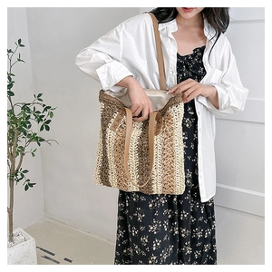Detail of multi-tone woven tote bag featuring leather handles and spacious interior