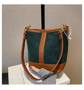 Detailed view of the dark green suede bucket bag with contrast brown leather stitching