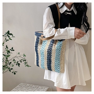 Detail of woven tote bag showing blue striped texture and brown leather straps