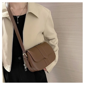 Detailansicht einer braunen Leder-Satteltasche mit Ziernaht und verstellbarem Gurt am Model