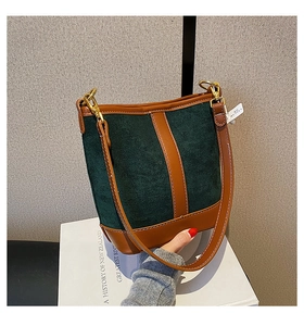 Detail of dark green suede bucket bag with brown leather trim and golden hardware