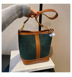 Close-up of contrast color bucket bag in green suede and brown leather with gold buckle