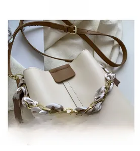 Detail of cream bucket bag featuring leopard print scarf wrapped gold chain handle