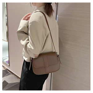 Model trägt vintage braune Leder-Satteltasche mit langem Schultergurt in weichem Interieur