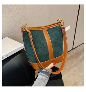 Detail of vintage green suede bucket bag with brown leather trim and gold hardware hooks