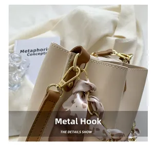 Detail of golden hardware hook and leopard print silk scarf on a beige bucket bag