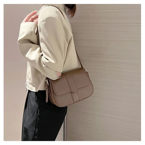 Seitenansicht einer braunen Vintage-Satteltasche aus Leder zum beigen Blazer
