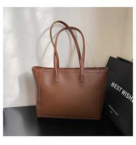 Macro view of brown tote bag with natural grain faux leather and refined stitching detail