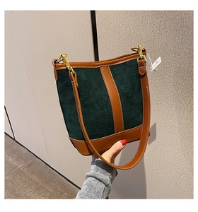 Detail of vintage dark green suede bucket bag with brown leather patchwork and gold hooks