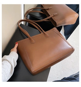 Detailed view of the brown leather tote bag with sturdy handles for daily commuting