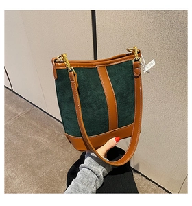 Close-up of color-block bucket bag with dark green suede and brown leather trim