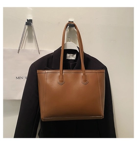 Detail of a large brown leather tote bag with long handles for stylish commuting