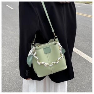 Street style view of a pistachio green bucket bag with floral scarf on a model