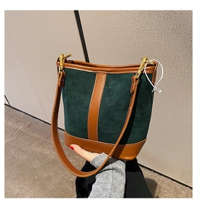 Detail of dark green suede bucket bag with brown leather trim and gold hardware