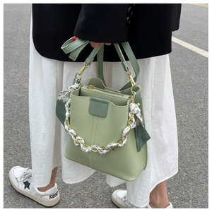 Detail of light green bucket bag with silk scarf chain handle and leather strap
