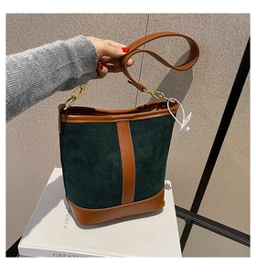 Close-up of retro bucket bag featuring green suede material and brown leather stitching