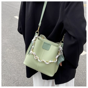 Detail of light green bucket bag with chain scarf handle and sleek leather stitching