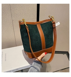 Detail view of contrast color bucket bag with green suede and brown leather trim