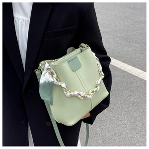 Detail of light green bucket bag with gold chain and floral scarf wrapped handle