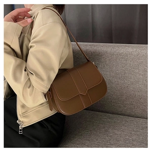 Detailansicht einer braunen Satteltasche aus Leder mit Ziernähten und Schnalle am Modell