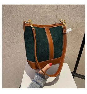 Close-up of green suede bucket bag with brown leather strap and gold hardware