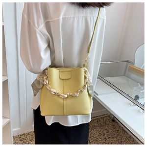 Detail of yellow bucket bag with metal chain handle and polka dot scarf accessory