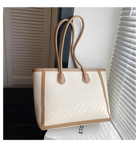 Detail of contrast cream and brown large tote bag with slim shoulder straps and reinforced edges