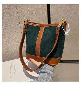 Detail of dark green suede bucket bag with brown leather base and gold metal hook