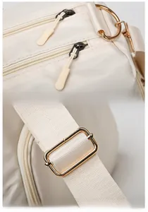 Detail of durable gold-plated hardware and adjustable shoulder strap buckle on cream travel bag