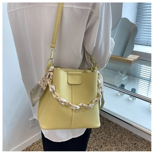 Detail of yellow bucket bag featuring a leopard print scarf wrapped on the chain handle