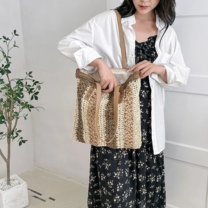 Large hand-woven straw tote bag with striped pattern and leather shoulder straps