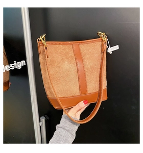 Detail of brown vintage bucket bag with suede texture and golden metal buckle