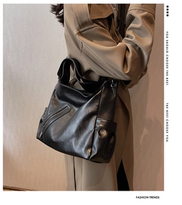 Détail du sac hobo vintage noir avec large bandoulière et poches latérales sur trench-coat