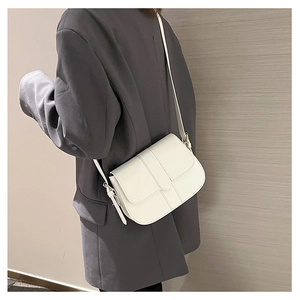 Detailansicht der weißen Satteltasche aus Kunstleder über einem dunkelgrauen Blazer