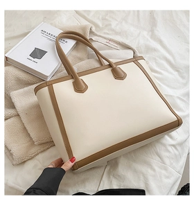 Detail of minimalist tote bag with contrast stitching and dual handles on soft sheets