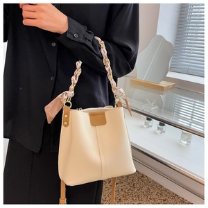 Detail of cream bucket bag with silk scarf wrapped chain handle on a black shirt