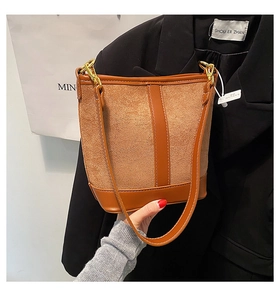 Detail of vintage brown bucket bag with suede patchwork and gold metal hardware hooks