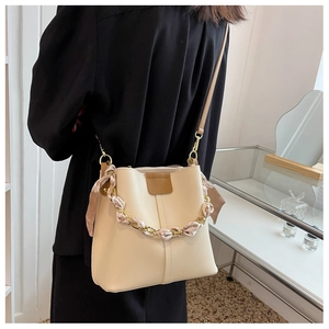 Detail view of cream bucket bag with silk scarf wrapped chain and golden hardware