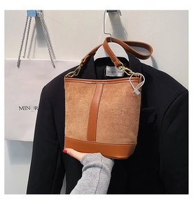 Detail of brown patchwork bucket bag featuring matte suede and smooth leather textures