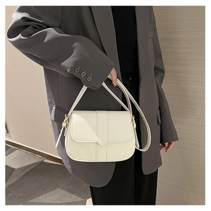 Seitenansicht der cremeweißen Leder-Satteltasche getragen mit einem Blazer für den Alltag