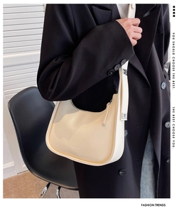 Close-up of a cream white hobo bag worn by a model in a modern urban setting
