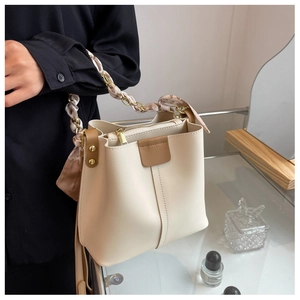 Detail of off-white bucket bag with elegant silk scarf chain handle and gold hardware