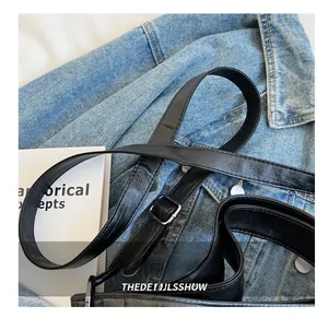 Détail de la bandoulière réglable en cuir PU avec boucle argentée sur un sac noir