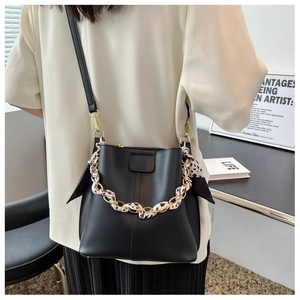 Detail of black leather bucket bag with leopard print silk ribbon and gold chain strap