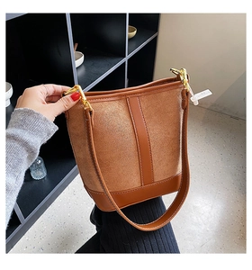 Detail of brown suede and smooth leather bucket bag with golden hardware accents