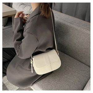 Detail einer cremeweißen Satteltasche aus Leder mit Klappverschluss und verstellbarem Riemen