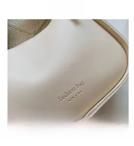Close-up of cream textured faux leather with embossed fashion bag New York logo and stitching
