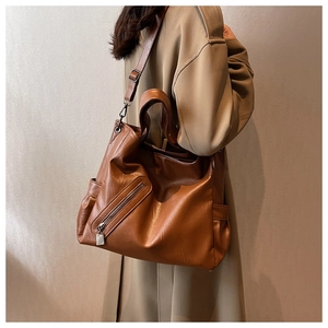Détail d'un grand sac cabas en cuir marron avec large bandoulière porté par un mannequin