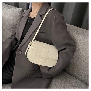 Schicke cremefarbene Satteltasche am Model im minimalistischen Blazer für Business-Look